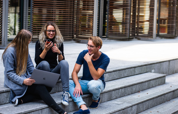 Tre personer som sitter på en trappa och diskuterar